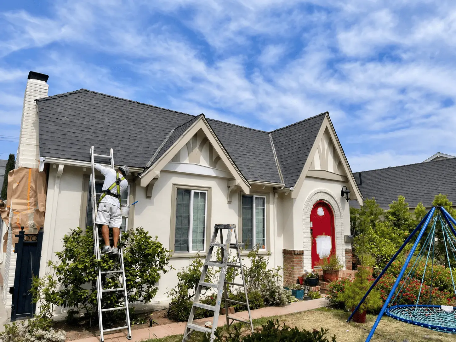 Foothill painter on a ladder cutting in trim on a cottage exterior
