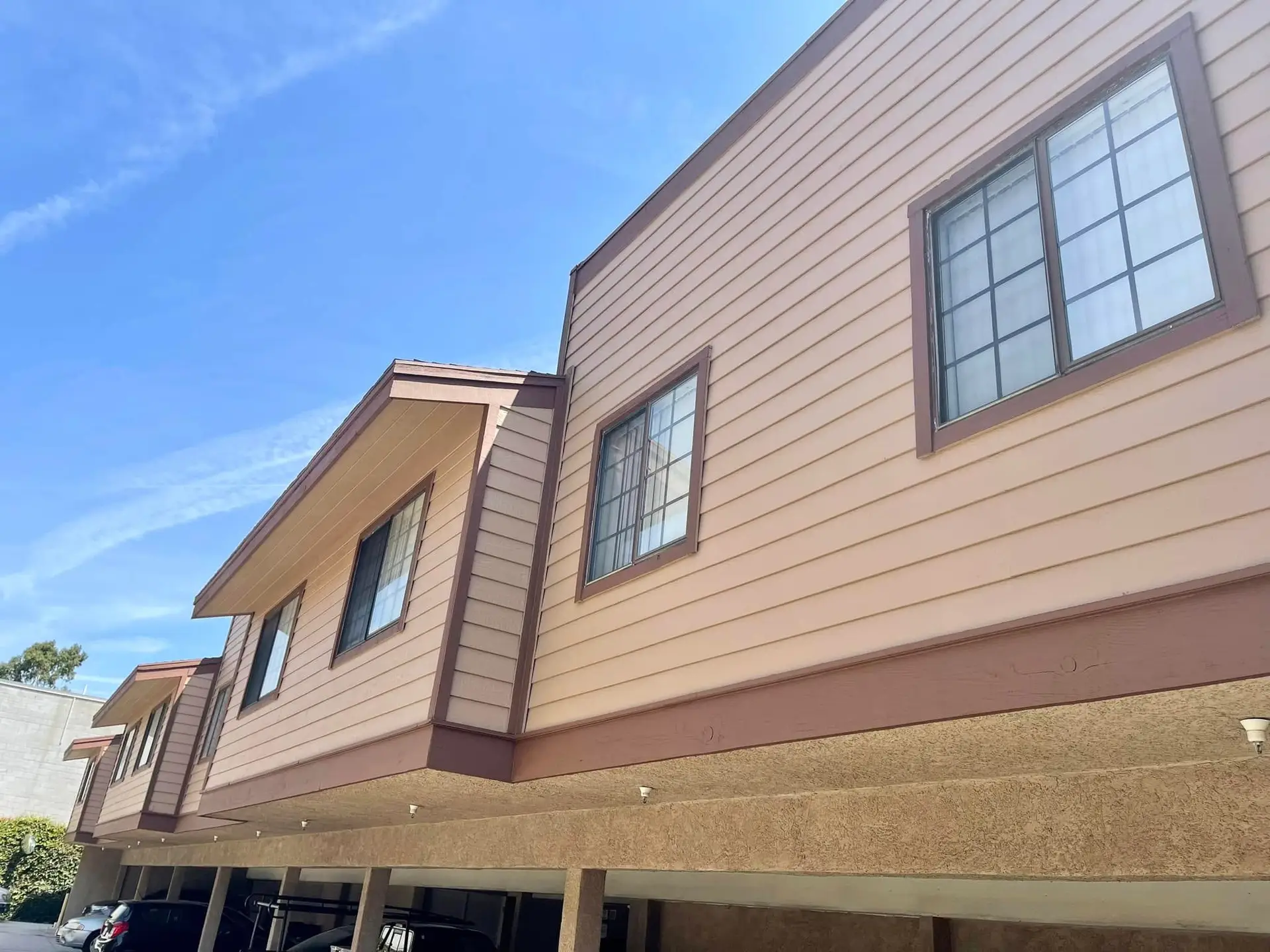 Dusty rose lap siding and painted window trim on the upper floor of a two-story building