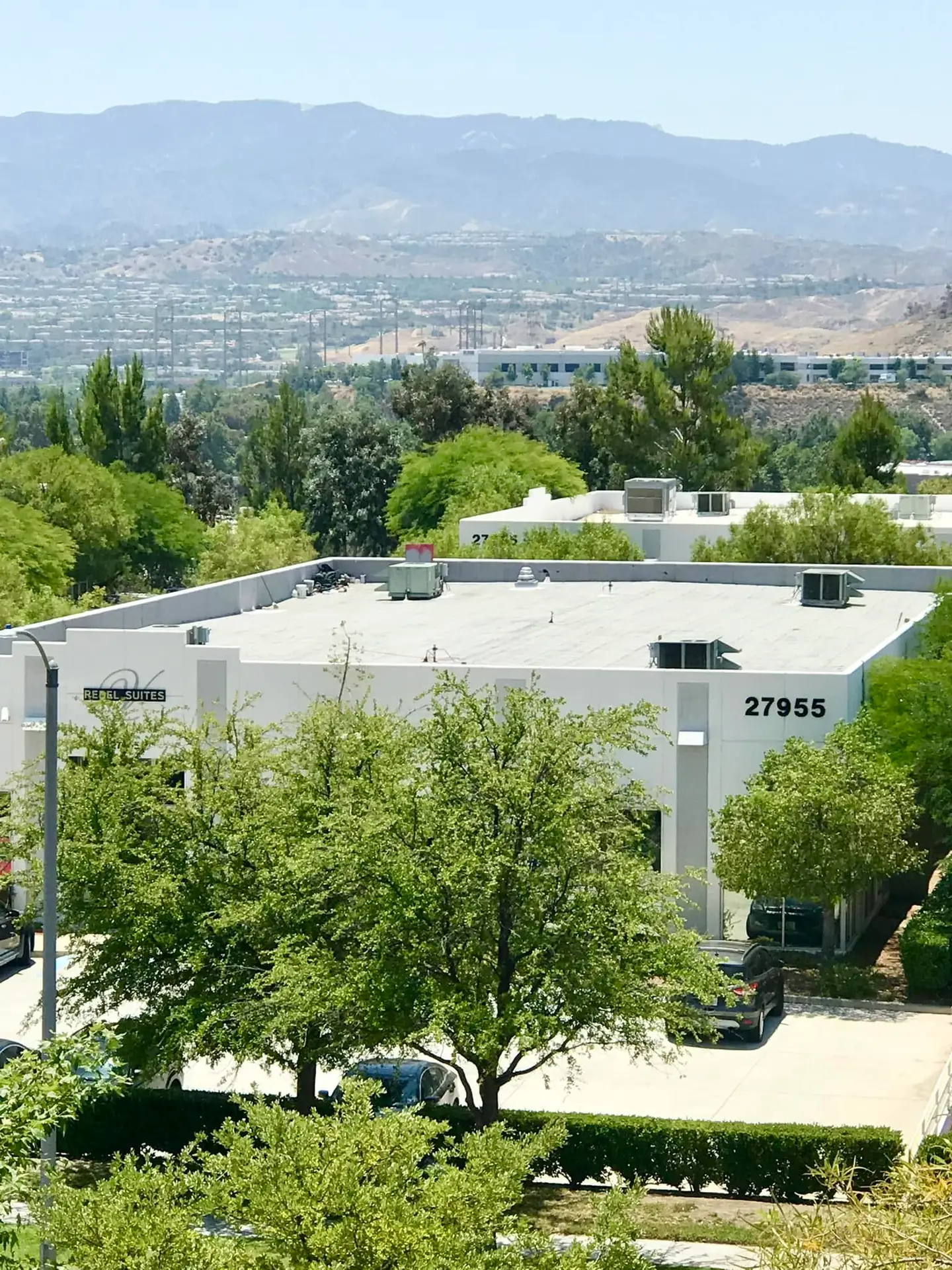 Flat white commercial rooftops spread across the valley below the San Gabriel foothills