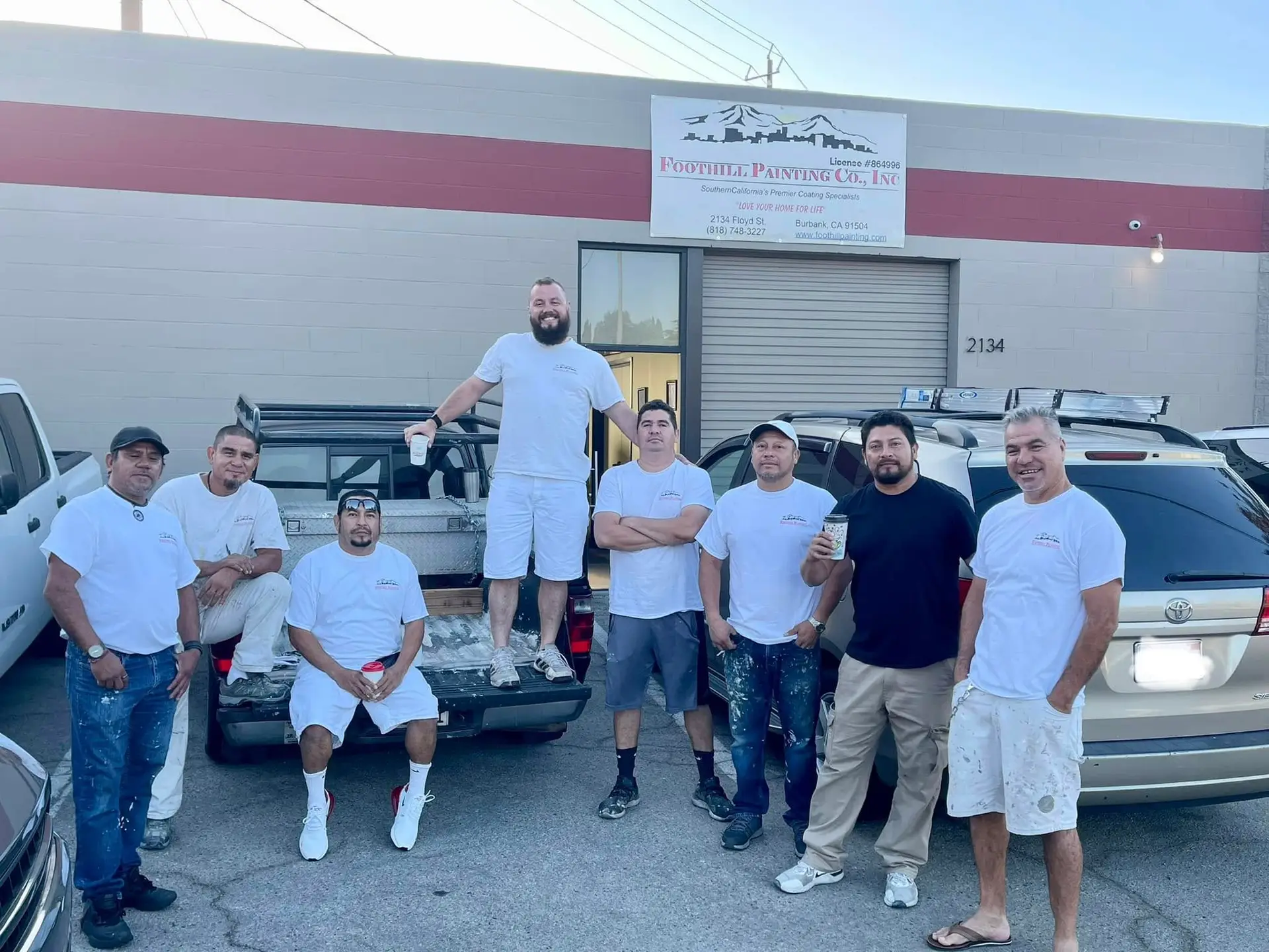 Eight Foothill Painting crew members gathered around a work truck at the Burbank shop