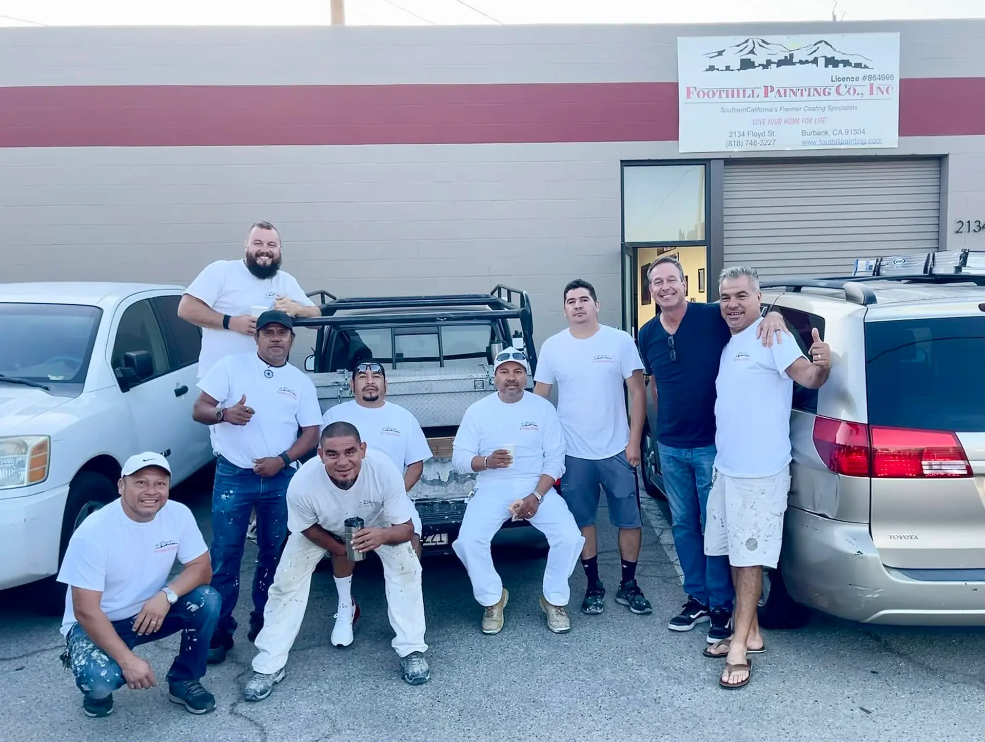 Foothill Painting crew in white work clothes standing with their trucks outside the company shop in Burbank