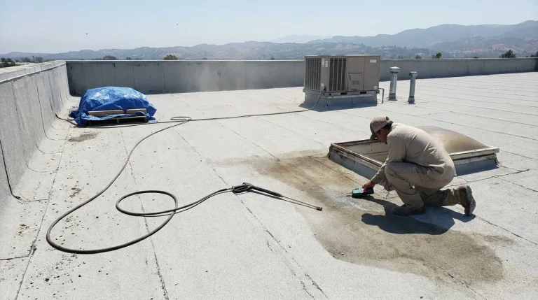 Worker checks roof dryness with a moisture meter on a Los Angeles area commercial flat roof before coating